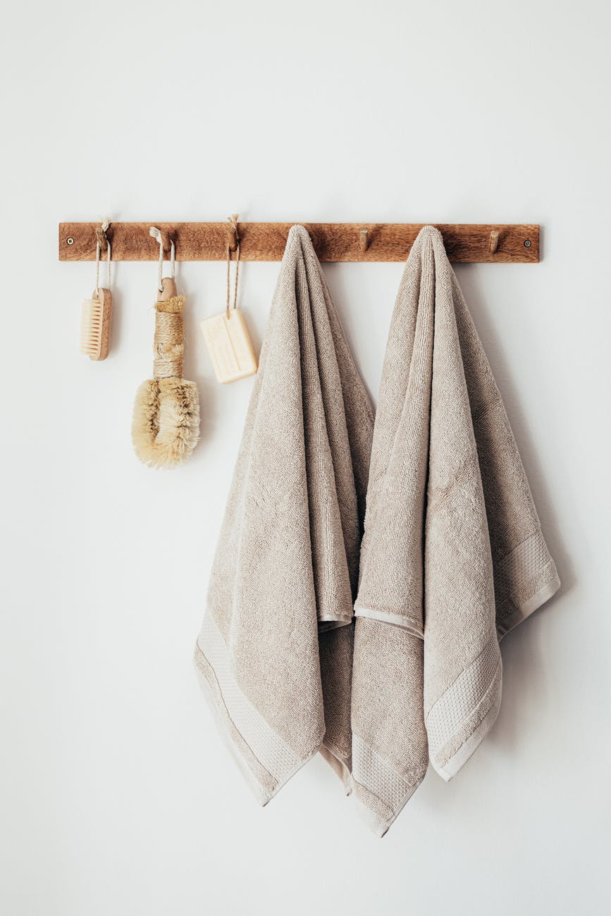 wooden hanger with towels and natural bathroom tools