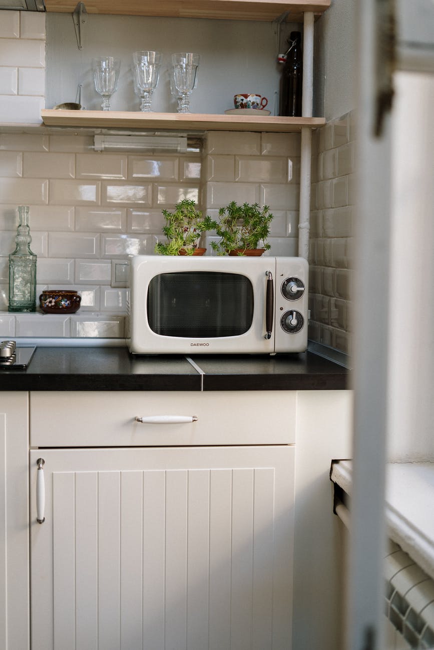 silver microwave oven on white wooden cabinet